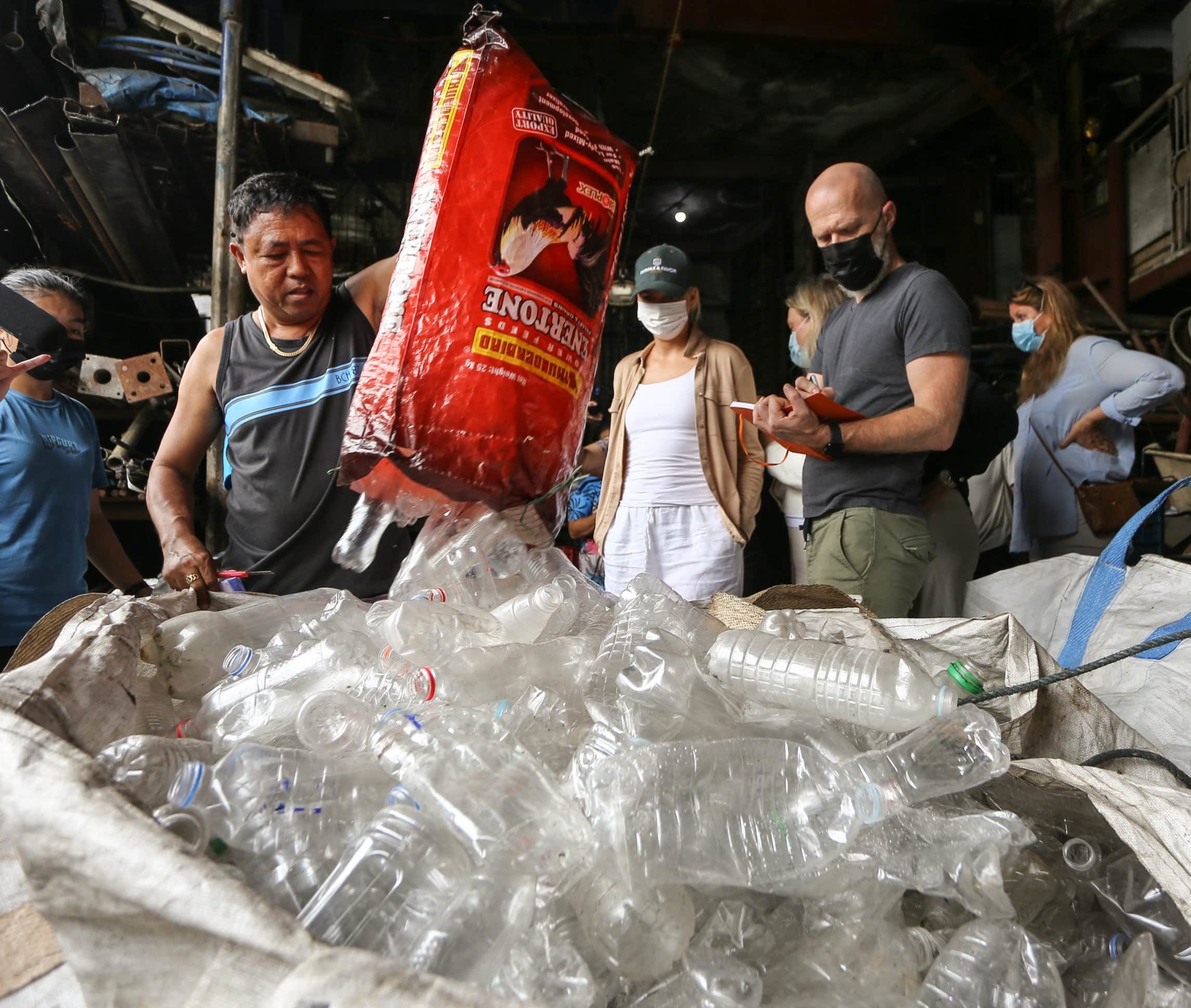 Man pours plastic bottles in a big bag at the plastic flamingo plastic recyclers workshop
