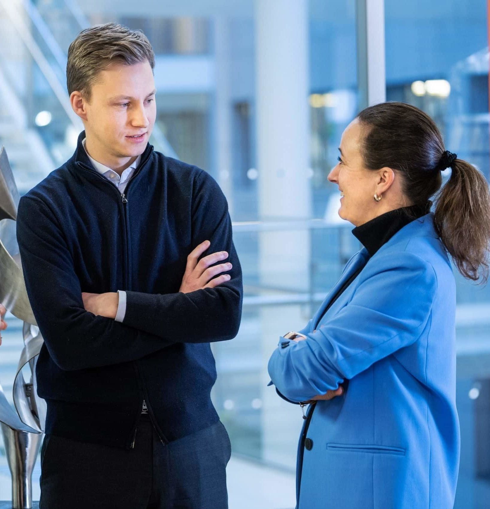 Male and Female employees talking to each other - Grieg Investor.