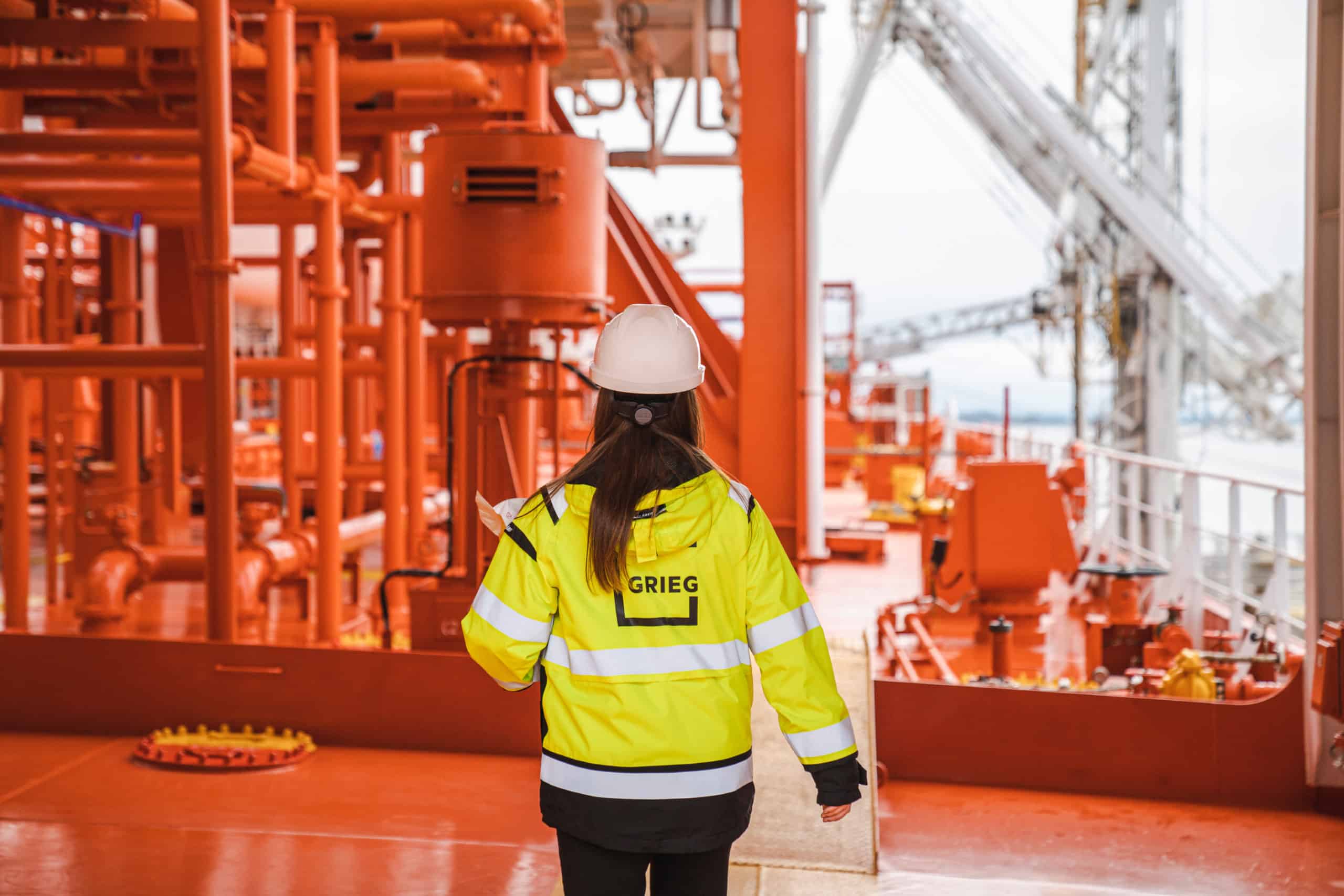 Female employee walking on deck of a cargo ship - Grieg Logistics.