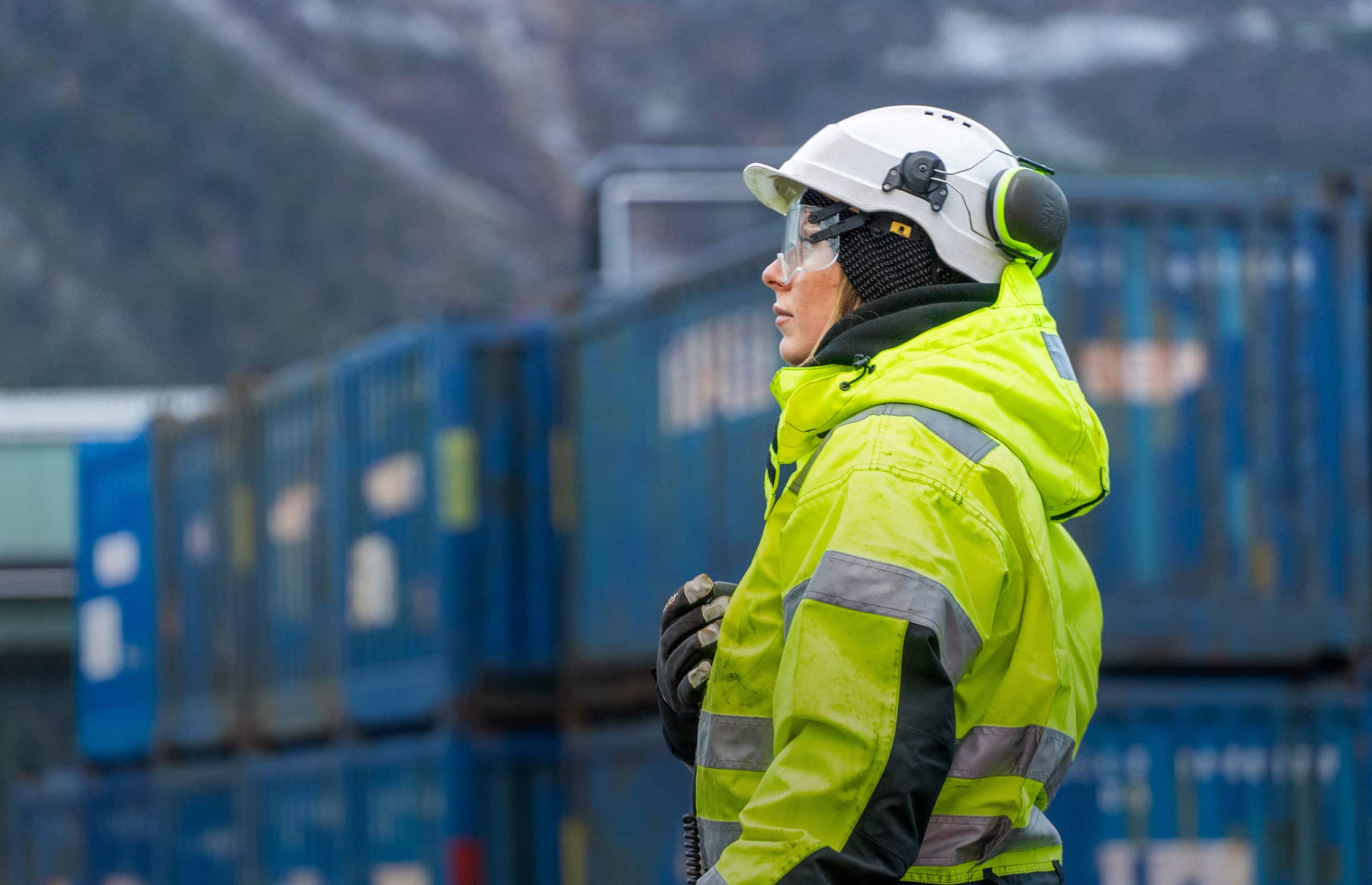 Female employee stands in workwear with a radio - Grieg Logistics.