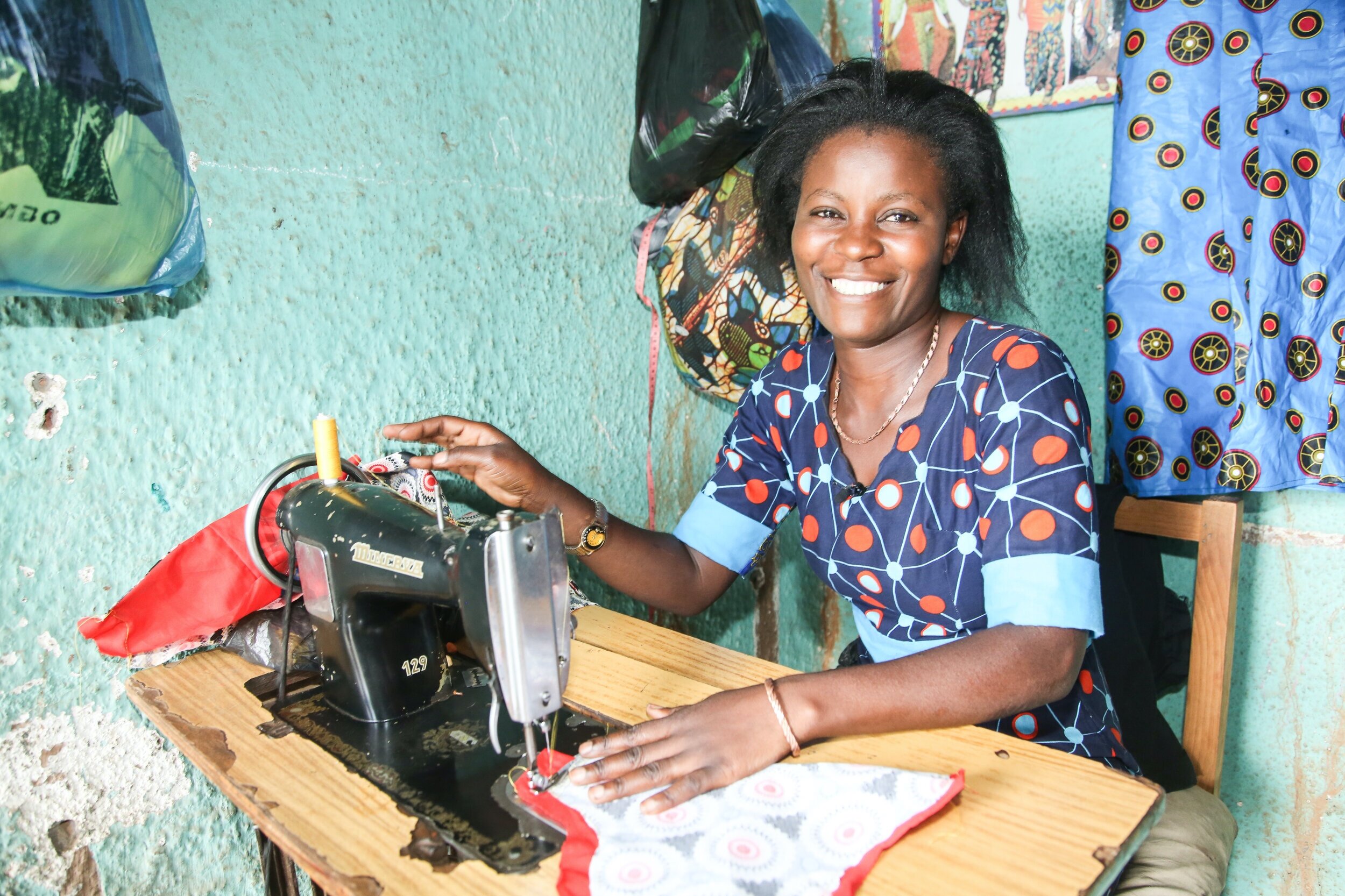 Smiling lady sewing in Rwanda.